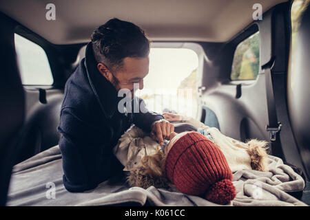 Junger Mann und Frau in Liebe liegen im Kofferraum und lächelnd. Romantische junge Paare im Kofferraum ruht. Stockfoto