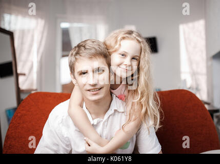 Happy fröhlich Vater und Tochter gemeinsam auf dem roten Sofa zu Hause Stockfoto