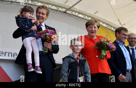 St. Peter-Ording, Deutschland. 21 Aug, 2017. Die deutsche Bundeskanzlerin Angela Merkel (CDU) auf der Bühne mit kleine Felix bei einer CDU-Wahlkampfveranstaltung in St. Peter-Ording, Deutschland, 21. August 2017. Auf der linken Seite ist der Ministerpraesident von Schleswig-Holstein Daniel Günther (CDU) mit wenig Katerina. Bundestagsabgeordnete Johann Wadephul zu Merkel und CDU-Generalsekretaer Peter Tauber ist auf der rechten Seite. Foto: Carsten Rehder/dpa/Alamy leben Nachrichten Stockfoto