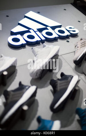 München, Deutschland. 21 Aug, 2017. Das Logo der Sportartikelunternehmen Adidas auf einer Wand über Adidas Schuhe in einem Store in München, Deutschland, 21. August 2017. - Keine LEITUNG SERVICE - Foto: Andreas Gebert/dpa/Alamy leben Nachrichten Stockfoto