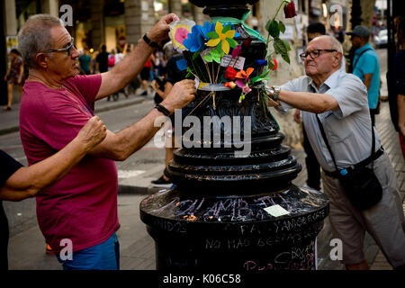 Barcelona, Katalonien, Spanien. 21 Aug, 2017. Zwei Männer statt Blumen an einem Laternenpfahl von Las Ramblas von Barcelona in Erinnerung an den Terror Angriff Opfer noch am gleichen Tag, Younes Abouyaaqoub, als Fahrer von Van, die Las Ramblas hinunter am Donnerstag sped identifiziert, ist erschossen worden von dem katalanischen Polizisten im Dorf Subirats. Credit: Jordi Boixareu/ZUMA Draht/Alamy leben Nachrichten Stockfoto