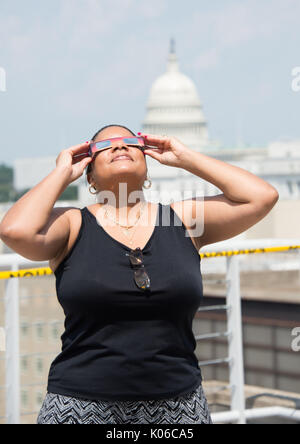 Washington, Vereinigte Staaten von Amerika. 21 Aug, 2017. Die NASA Angestellten Denise Junge verwendet eine Schutzbrille, um eine partielle Sonnenfinsternis vom NASA-Hauptquartier auf dem Dach August 21, 2017 in Washington, DC. Die totale Sonnenfinsternis über einem schmalen Teil des angrenzenden Vereinigten Staaten von Oregon nach South Carolina und eine partielle Sonnenfinsternis war über den gesamten nordamerikanischen Kontinent sichtbar zusammen mit Teilen von Südamerika, Afrika und Europa. Credit: Planetpix/Alamy leben Nachrichten Stockfoto