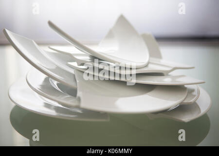 Stapel gebrochen weiße Platten auf Glas Tisch Stockfoto