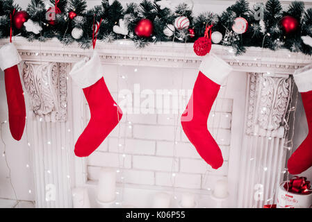 Ein Bild schließen der schön dekorierten hellen roten Weihnachten Socken hängen an einem Kamin warten auf präsentiert. Stockfoto