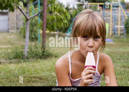 Schönes Kind essen Eis im Freien in Spring Park gegen natürliche grüner Hintergrund Stockfoto