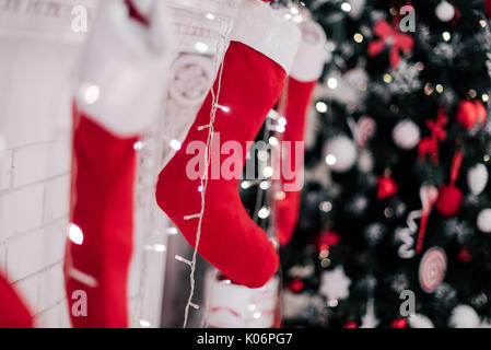 Ein Bild schließen der schön dekorierten hellen roten Weihnachten Socken hängen an einem Kamin warten auf präsentiert. Stockfoto