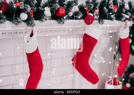 Ein Bild schließen der schön dekorierten hellen roten Weihnachten Socken hängen an einem Kamin warten auf präsentiert. Stockfoto