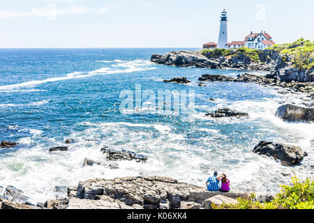 Cape Elizabeth, USA - 10. Juni 2017: Paar sitzt auf Felsen Felsen an der Portland Head Lighthouse in Fort Williams Park in Maine im Sommer, da Stockfoto