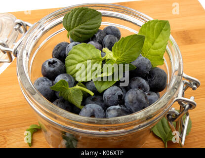 Blaubeeren in einem Glas auf einem Holzbrett Stockfoto