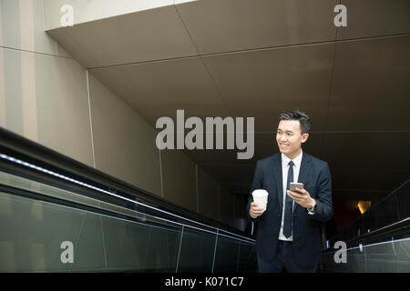 Chinesische Geschäft Mann in modernen asiatischen Stadt. Porträt eines asiatischen Geschäftsmann lächelnd und mit Blick auf die Kamera mit unscharfen Bürogebäude als backgro Stockfoto