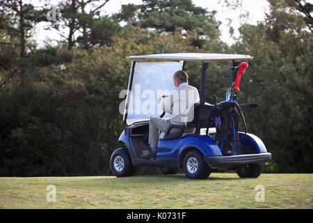 Ältere Golfspieler in einem Golf Buggy auf dem Kurs. Stockfoto