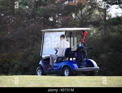 Ältere Golfspieler in einem Golf Buggy auf dem Kurs. Stockfoto