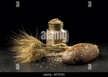 Korn Bouquet, goldenen Hafer Ährchen in jar auf dunklen Holztisch, Brötchen und können mit getrockneten Körnern gefüllt. Essen, Bäckerei Konzept Stockfoto