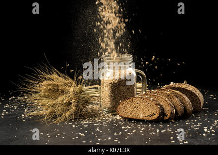 Korn Bouquet, goldenen Hafer Ährchen in jar auf dunklen Holztisch, Brötchen und können mit getrockneten Körnern gefüllt. Essen, Bäckerei Konzept Stockfoto