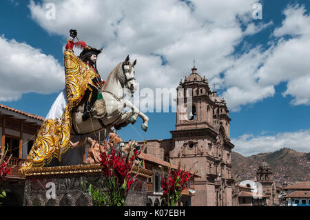 Eine Statue des Heiligen Jakobus mit Kirche La Compania de Jesus im Hintergrund, während Sie im Corpus Christi feiern an der Plaza de Armas, Cusco, Peru. Stockfoto