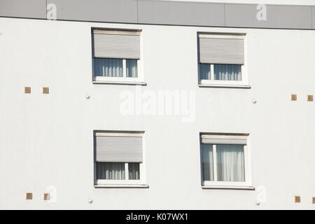 Windows mit geschlossenen Fensterläden auf einer weißen Hauswand Stockfoto