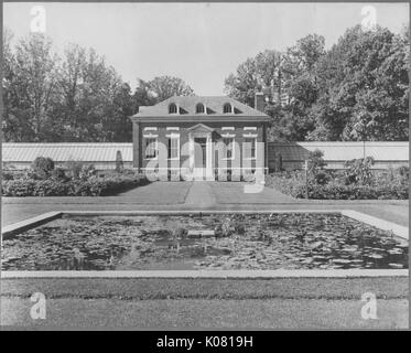 Foto von der Außenseite des Ziegels home mit Standard und Dachgauben, eine kleine Treppe, die zu einem Eingangsbereich, und Schornsteine, in einem aufwändig gepflegten Rasen mit einem reflektierenden Pool gelegen, dichten Bäumen hinter dem Haus, in einem ruhigen Wohngebiet von Baltimore, Maryland, 1910. Dieses Bild wird von einer Reihe dokumentieren den Bau und den Verkauf von Wohnungen in der Roland Park/Guilford Nachbarschaft von Baltimore, einer Straßenbahn Vorort und eines der ersten geplanten Gemeinschaften in den Vereinigten Staaten. Stockfoto