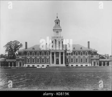 Ein Foto von der Außenseite des Gilman Hall auf dem Homewood Campus der Johns Hopkins University in Baltimore, Maryland, Landschaftsgestaltung und architektonische Elemente wie die Treppe, die zum Haupteingang, der Glockenturm, Standard- und Gauben, Kamine, klassischen Säulen, Baltimore, Maryland, 1970. Dieses Bild wird von einer Reihe dokumentieren den Bau und den Verkauf von Wohnungen in der Roland Park/Guilford Nachbarschaft von Baltimore, einer Straßenbahn Vorort und eines der ersten geplanten Gemeinschaften in den Vereinigten Staaten. Stockfoto