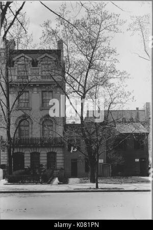 Foto von einer Straße in Baltimore von Roland Park Apartments, das Gebäude vier Stockwerke hoch mit großen verzierten Fenstern und detaillierte Frames, das Gebäude neben zwei kleinere Gebäude auf der Straße neben einem Bürgersteig sprießen große Bäume mit wenigen Blättern auf ihnen, United States, 1920. Dieses Bild wird von einer Reihe dokumentieren den Bau und den Verkauf von Wohnungen in der Roland Park/Guilford Nachbarschaft von Baltimore, einer Straßenbahn Vorort und eines der ersten geplanten Gemeinschaften in den Vereinigten Staaten. Stockfoto