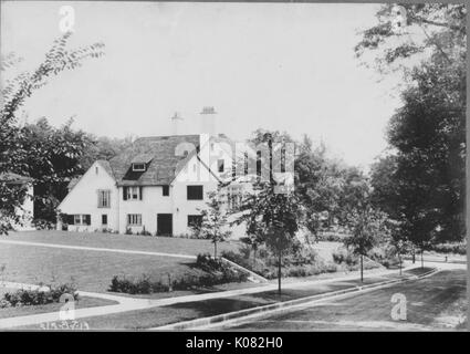 Ansicht von der Seite des hellen Haus mit mehreren Fenstern und Türen mit dunklen Platten, Schornstein auf Haus, Felder von Gras und konkrete Bürgersteige Umgebung Haus, viel Vegetation und Bäume Haus und Bürgersteige, Straße neben Haus, Baltimore, Maryland, 1910. Dieses Bild wird von einer Reihe dokumentieren den Bau und den Verkauf von Wohnungen in der Roland Park/Guilford Nachbarschaft von Baltimore, einer Straßenbahn Vorort und eines der ersten geplanten Gemeinschaften in den Vereinigten Staaten. Stockfoto