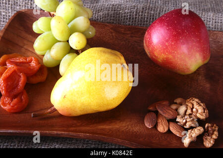 Frisches Bio-obst auf Holz, das Fach sortiert Äpfel, Birnen, Weintrauben, getrocknete Früchte und Nüsse. Stockfoto