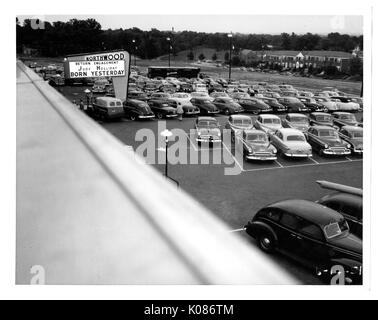 Foto geschossen oberhalb der Northwood Einkaufszentrum Parkplatz in Baltimore, mit Autos gefüllt, von einem beleuchteten Schild mit der Aufschrift "Northwood", mit vielen Bäumen int er Hintergrund, jedes Auto ordentlich in die weißen Linien, dass jeder Raum abgrenzen, Baltimore, Maryland, 14. Juni 1951 abgestellt. Stockfoto