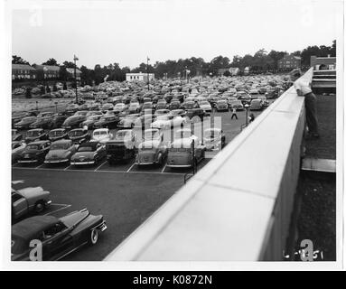 Foto geschossen oberhalb der Parkplatz des Northwood Shopping Center in Baltimore, mit Autos gefüllt, mit vielen Bäumen im Hintergrund, mit einem Jungen über einen Balkon auf alle Autos, Baltimore, Maryland, 7. Juni 1951. Stockfoto