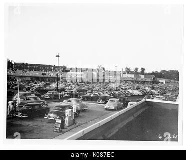 Parkplatz in Northwood Einkaufszentrum mit Hunderten von Autos, Tankstelle vor Foto mit mehreren Filialen in Boden zurück wie Acme Markt, viele Bäume und Straßenbeleuchtung im Hintergrund, Baltimore, Maryland, 1951. Stockfoto