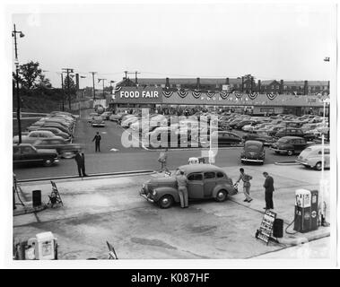 Parkplatz in Northwood Einkaufszentrum mit Hunderten von Autos, Restaurants und Geschäfte im Hintergrund als Essen Messe, Dekorationen mit Fahnen auf die Stores, Baltimore, Maryland, 1950. Stockfoto