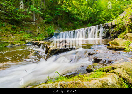 Schöne kleine Wasserfall auf der schönen Bach im Wald in der Tschechischen. Lange Belichtungszeit, milchiges Wasser Effekt, Bäume und grüne Gras um, Felsen und Steine Stockfoto