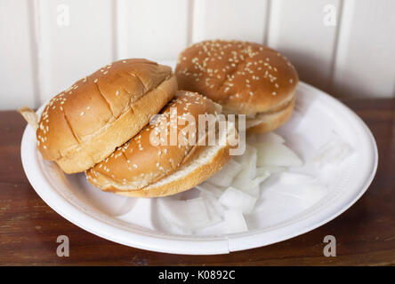 Drei Hamburger Brötchen auf einem Teller mit Zwiebeln Stockfoto