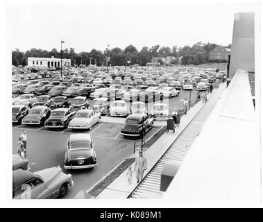 Foto von Parkplatz für die Northwood Shopping Center in Baltimore, Maryland, voller Autos, mit Gönner zu Fuß auf den Bürgersteigen, Wohn- und Geschäftshäuser und Bäume im Hintergrund, Baltimore, Maryland, 1951. Stockfoto