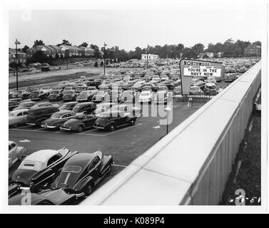 Foto von einem Parkplatz für die Northwood Shopping Center in Baltimore, Maryland, mit vielen Autos, Gönner gehen auf einem Bürgersteig, und ein Zeichen für den Film "Sie in der Marine Jetzt" mit Gary Cooper und Jane Greer, mit Wohnbauten und Bäume im Hintergrund, Baltimore, Maryland, 7. Juni 1951. Stockfoto