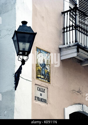 Eine religiöse Kunstwerke von keramischen Fliesen Marken Calle de San Francisco, eine Straße für den Hl. Franz von Assisi in der historischen Altstadt San Juan in Puerto Rico (PR), ein gemeindefreies Gebiet der Vereinigten Staaten im karibischen Meer genannt. Ein vintage Schmiedeeisen Straße Licht der Straße Name aufleuchtet und illustrierte Zeichen in der Nacht. Stockfoto