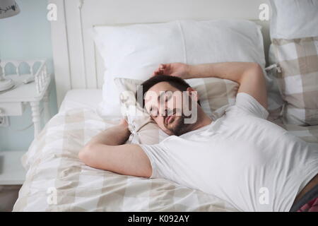 Schöner Mann schlafen auf Kissen im Bett Stockfoto