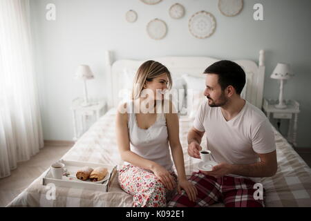 Bild von jungen glückliches Paar sitzt auf dem Bett Stockfoto