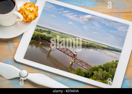 Historische Eisenbahn Katy Brücke über Missouri Boonville - Überprüfung Luftbild auf einem digitalen Tablette mit einer Tasse Kaffee Stockfoto