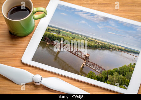 Historische Eisenbahn Katy Brücke über Missouri Boonville - Überprüfung Luftbild auf einem digitalen Tablette mit einer Tasse Kaffee Stockfoto