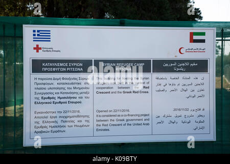 Ein Schild am Eingang Ritsona Flüchtlingslager in Griechisch, Englisch und Arabisch erzählt von Zusammenarbeit der Griechischen Roten Kreuz und Roten Halbmond Emirates. Stockfoto