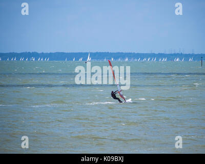 Ein Wind surfer Segel auf den Solent mit der Isle of Wight im Hintergrund. Stockfoto