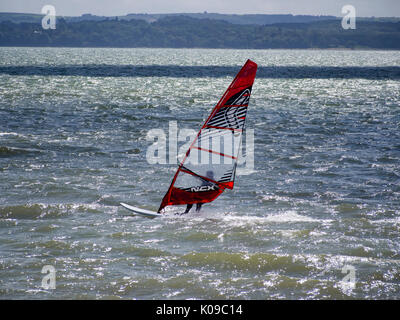 Ein Wind surfer Segel auf den Solent mit der Isle of Wight im Hintergrund. Stockfoto