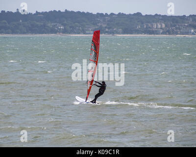 Ein Wind surfer Segel auf den Solent mit der Isle of Wight im Hintergrund. Stockfoto