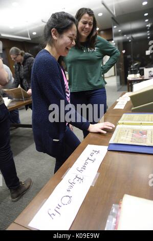 Zwei weibliche Studenten an einer Probe lachend auf einem Tisch, der über das Zeichen, "Nur der lüsternen Augen', 11. Februar 2016. Stockfoto