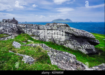 Eine brüchige Struktur sitzt entlang der felsigen irische Küste mit dem Blasket Islands im Hintergrund Stockfoto