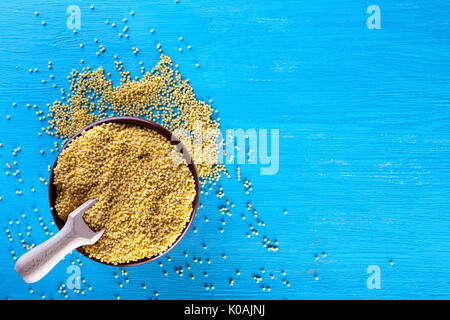 Ton Schüssel mit Hirse auf einem blauen Hintergrund Stockfoto