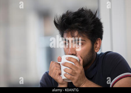 Porträt einer asiatischer Mann zu Hause trinken eine heiße Tasse Kaffee oder Tee. Stockfoto