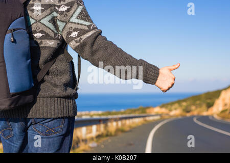 Reise, Reisen, Geste und Personen Konzept - Mann per Anhalter fahren und anhalten Auto mit Daumen nach oben Geste auf die Landschaft. Stockfoto