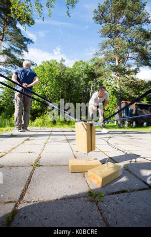 Glücklicher Mann Picking Holzklötze von Freund auf der Terrasse Stockfoto