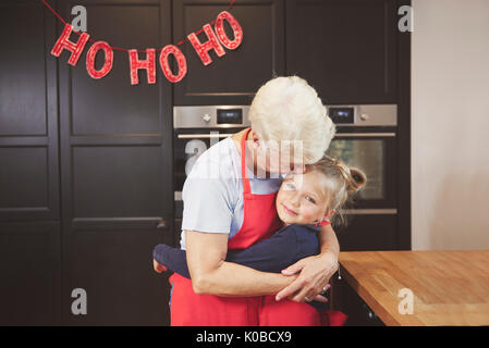 Oma mit Enkelin umarmen in der Küche Stockfoto