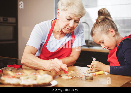 Oma mit Mädchen backen und dekorieren cookies zusammen Stockfoto